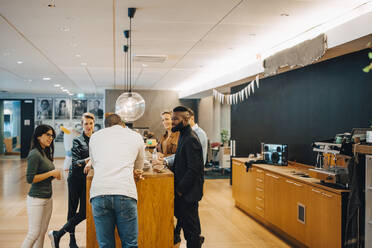 Geschäftsleute diskutieren während eines Treffens in der Cafeteria im Büro - MASF22965