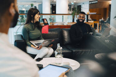 Lächelnde männliche und weibliche Kollegen diskutieren bei einem Treffen im Büro - MASF22983