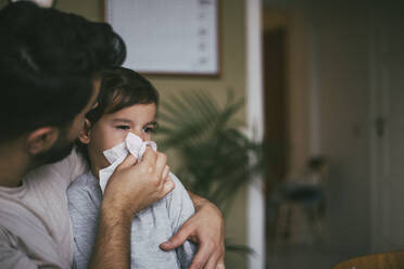 Father blowing nose of sick son at home - MASF23025
