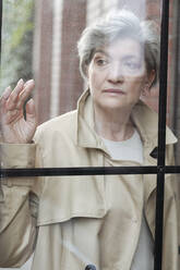 Mature woman looking away through glass - VYF00472