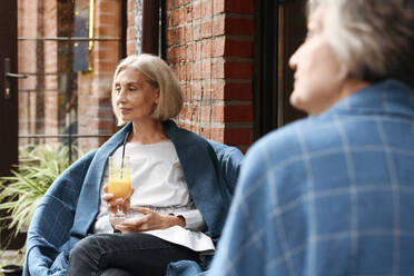 Mature female friends sitting at sidewalk cafe - VYF00492