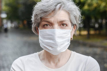 Ältere Frau mit Gesichtsschutzmaske bei COVID-19 - VYF00509