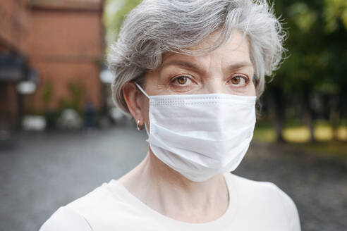 Ältere Frau mit Gesichtsschutzmaske während einer Pandemie - VYF00513