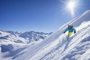Sun shining over woman skiing in Arlberg massif - RNF01301