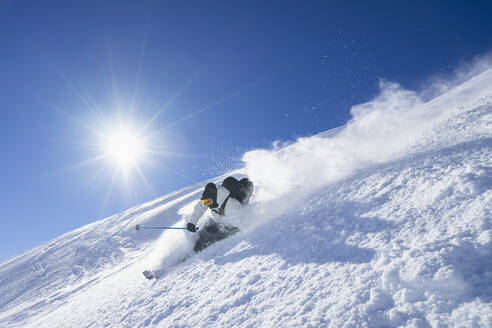 Die Sonne scheint über einem jungen Mann beim Skifahren im Arlberg-Massiv - RNF01302