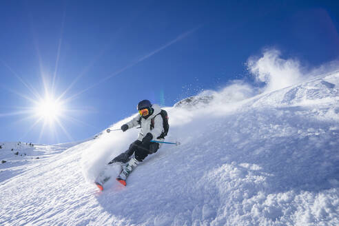 Die Sonne scheint über einem jungen Mann beim Skifahren im Arlberg-Massiv - RNF01304