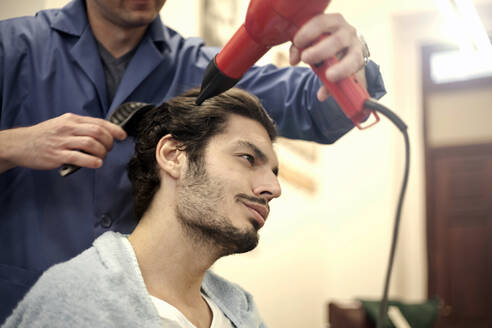 Friseur, der das Haar eines männlichen Kunden trocknet - AJOF01302