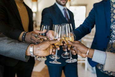 Hände von eleganten Männern, die bei einem Bankett mit Champagner anstoßen - EGAF02263