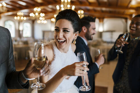 Male and female friends drinking champagne and laughing at banquet - EGAF02280