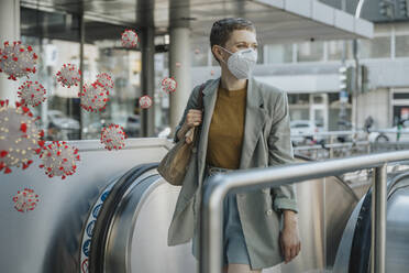 Corona viruses in front of woman with face mask on escalator - LIFIF00008
