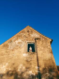 Garden gnome at window of weathered house - BRF01504