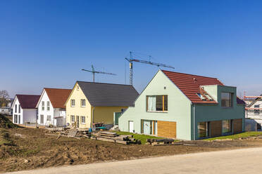 Deutschland, Baden-Württemberg, Ludwigsburg, Klarer Himmel über modernem Neubaugebiet mit Industriekränen im Hintergrund - WDF06565