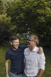 Lachender Sohn, der seinen Vater umarmt, während er im Hinterhof steht - GUSF05555