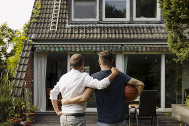 Vater und Sohn mit Arm um stehend vor dem Haus - GUSF05613