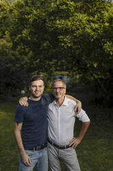 Son and father with arm around standing in back yard - GUSF05650