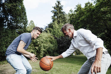 Vater spielt Basketball mit Sohn im Hinterhof an einem sonnigen Tag - GUSF05670