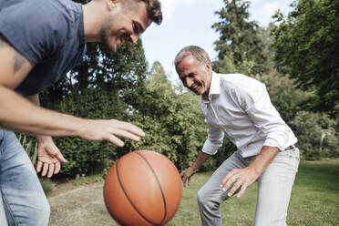 Playful father and son with basketball in backyard - GUSF05671