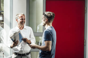 Son discussing with father holding newspaper at home - GUSF05721