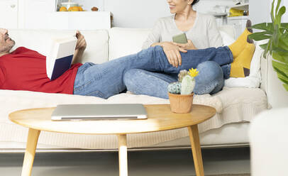 Couple discussing with each other while relaxing on sofa at home - JCCMF01650