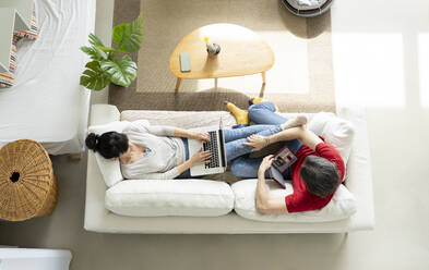 Couple relaxing on sofa in living room at home - JCCMF01652