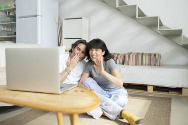 Reifes Paar gestikuliert während eines Videoanrufs auf dem Laptop zu Hause - JCCMF01700
