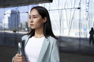 Businesswoman looking away while standing in front of office building - VEGF04160