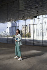 Weibliche Unternehmerin steht vor einem gläsernen Bürogebäude - VEGF04163