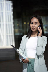 Young businesswoman talking on phone while looking away - VEGF04170