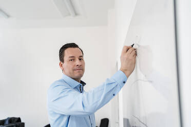 Männliche professionelle Zeichnung Tabelle auf Whiteboard im Büro - DIGF14952