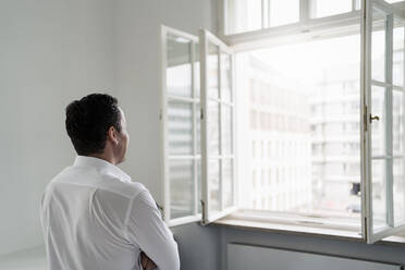 Male professional looking through window at office - DIGF14966