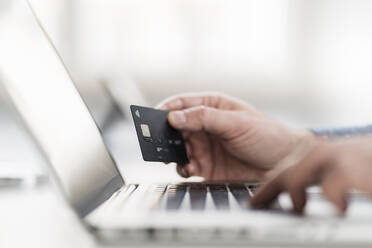 Hand of businessman using laptop while holding credit card at workplace - DIGF14977