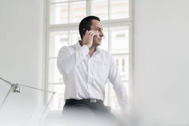 Male entrepreneur talking on phone at workplace - DIGF14989