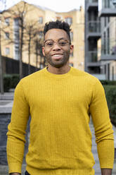 Lächelnder Mann im gelben Pullover mit Brille - FBAF01760