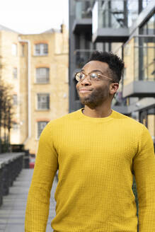 Young man in yellow sweater looking away - FBAF01762