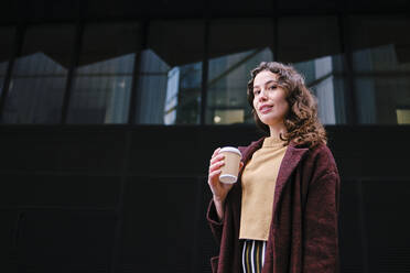 Schöne Frau beim Kaffee trinken vor einem Glasgebäude stehend - ASGF00105