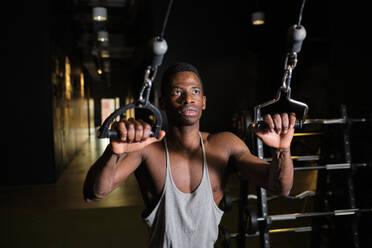 Afrikanischer Mann übt Suspensionstraining im Fitnessstudio - AODF00439