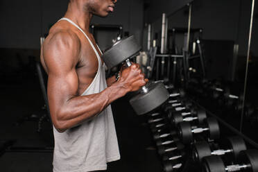 Athletic young male exercising with dumbbells at gym - AODF00448