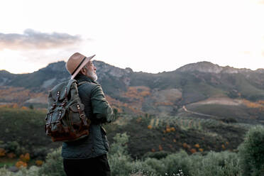 Back view of elderly male wanderer standing on hill and admiring scenic view of highlands in Caceres - ADSF22479