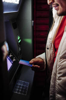 Junger Mann benutzt Debitkarte am Geldautomaten - ASGF00145