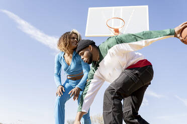 Glücklicher Mann und Frau spielen Basketball auf dem Platz - JCCMF01732