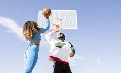 Male and female playing basketball on sports court - JCCMF01734