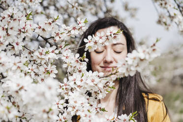 Beautiful woman seen through white flowers during springtime - EBBF03099