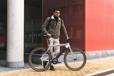 Gut aussehender Geschäftsmann mit Fahrrad auf dem Fußweg stehend - JAQF00450