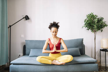 Junge Frau übt Yoga auf dem Sofa zu Hause - JCZF00626
