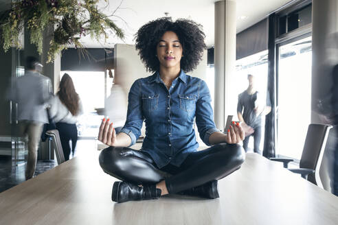 Young female professional meditating on conference table at office - JSRF01499