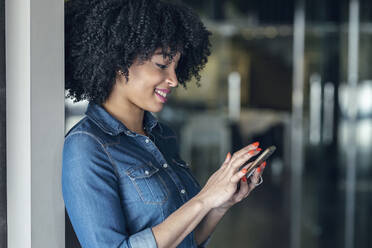 Smiling female entrepreneur using smart phone at office - JSRF01500