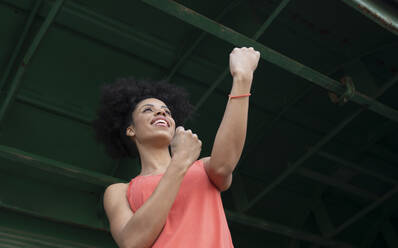 Woman making boxing gesture under iron shed - JCCMF01760