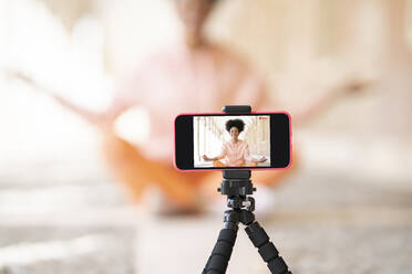 Woman filming herself through smart phone while doing yoga - JCCMF01773