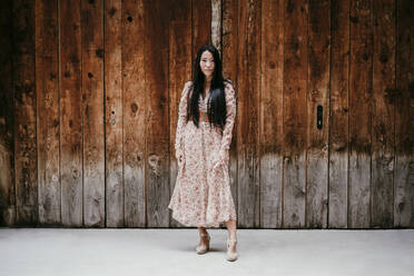 Beautiful woman standing by old wooden door - EBBF03202