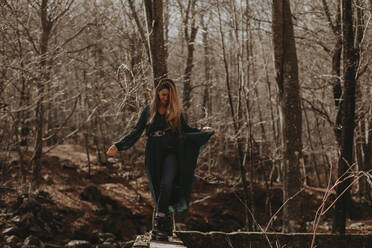 Woman walking on retaining wall in forest during autumn - GMLF01133